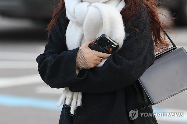 A pedestrian bundled up in winter clothing walks near Gwanghwamun Plaza in central Seoul on Dec. 13, 2023. (Yonhap)