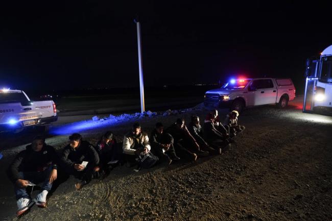 FILE - Migrants wait to be processed to seek asylum after crossing the border into the United States, Friday, Jan. 6, 2023, near Yuma, Ariz. (AP Photo/Gregory Bull, File)