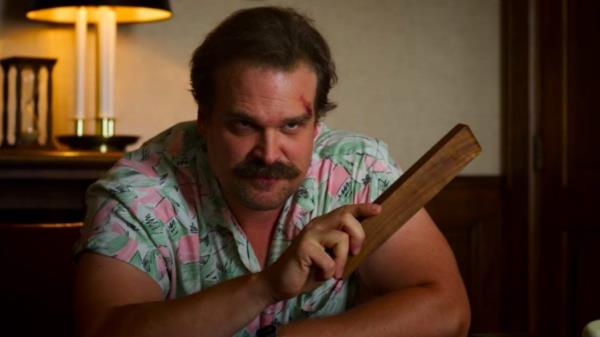 David Harbour as Jim Hopper in Stranger Things holding a piece of wood